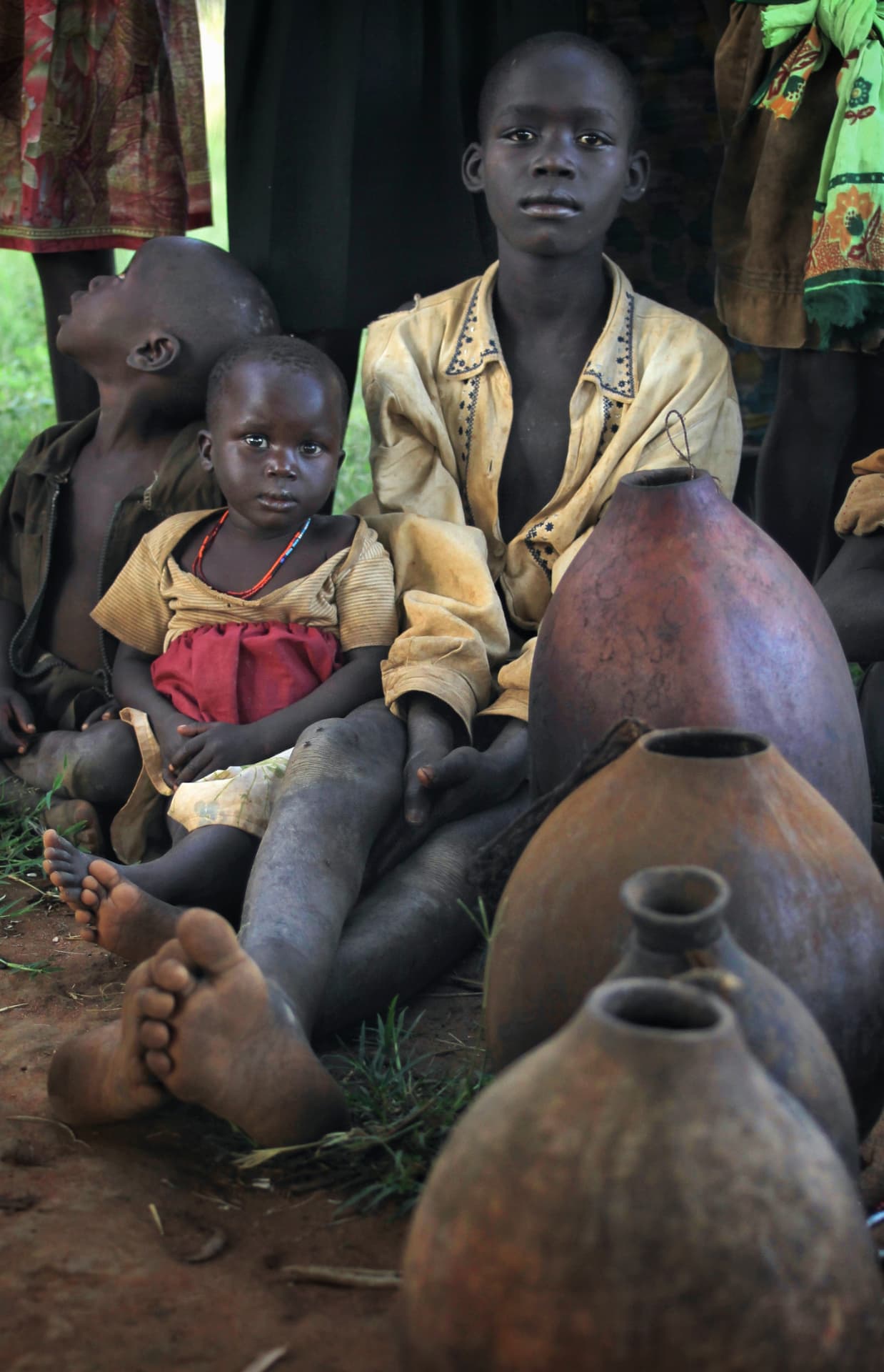 Lurukul children sitting beside clay pots
